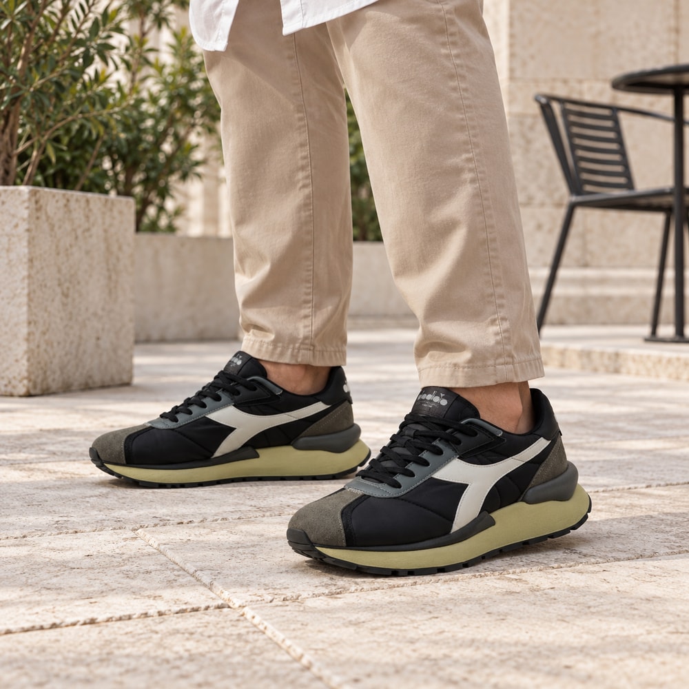 Ambientación con IA: Zapatillas Diadora Mercury Elite de hombre en negro, puesto con pantalones.