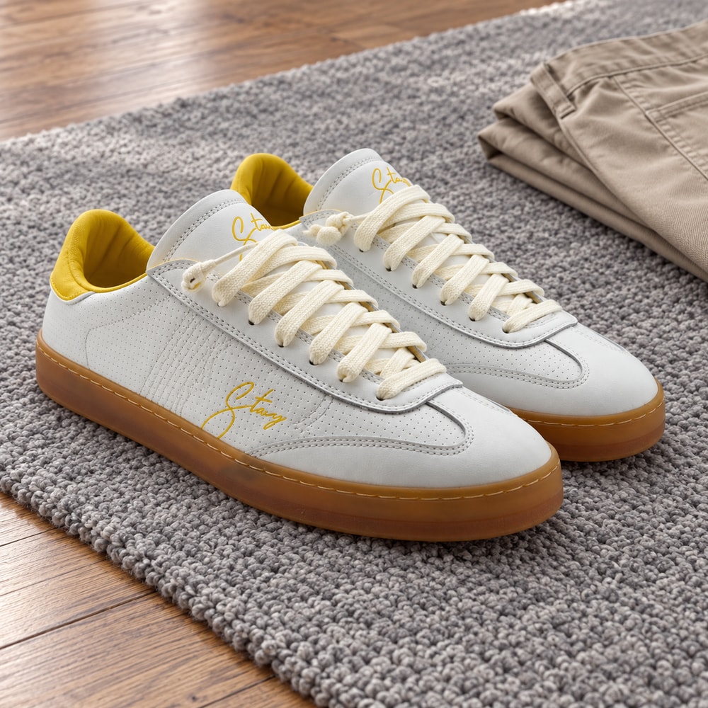 Ambientación con IA: Zapatillas Stacy Lotus de hombre en blanco y amarillo, junto a prendas lisas.