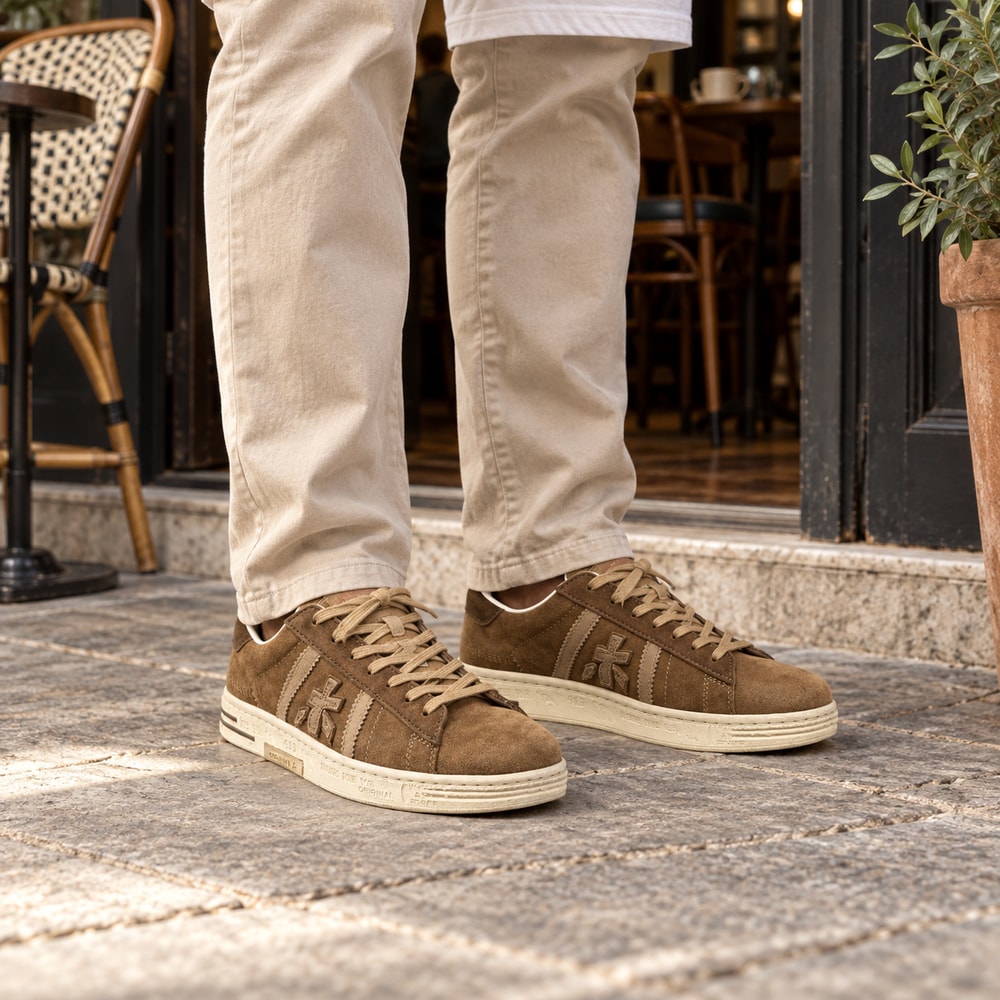 Ambientación con IA: Zapatillas Premiata Russell de hombre en color cuero, puesto con pantalones.