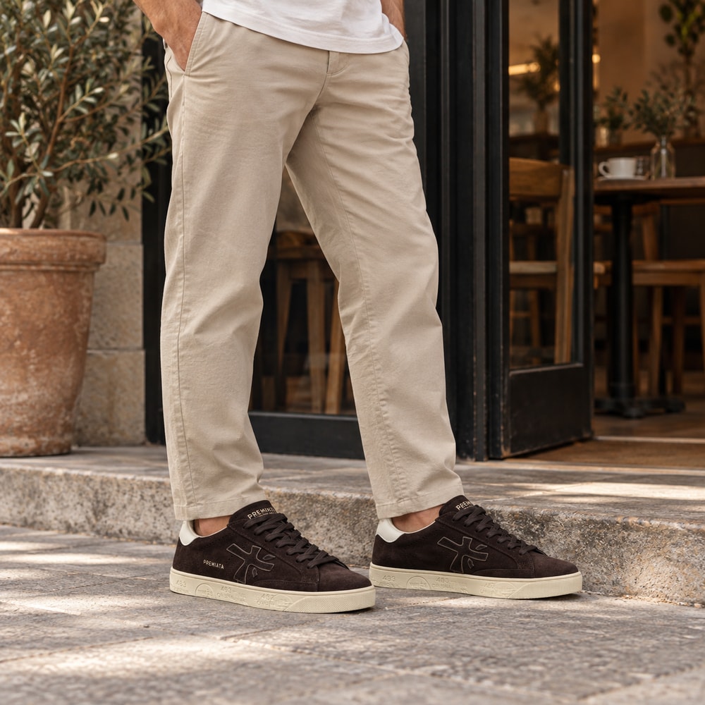 Ambientación con IA: Zapatillas Premiata Steven de hombre en marrón, puesto con pantalones.