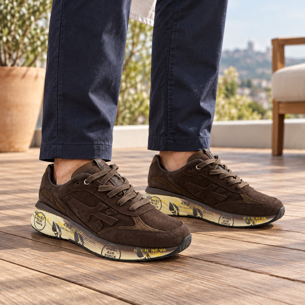 Ambientación con IA: Zapatillas Premiata Moerun de hombre en color chocolate, puesto con pantalones.