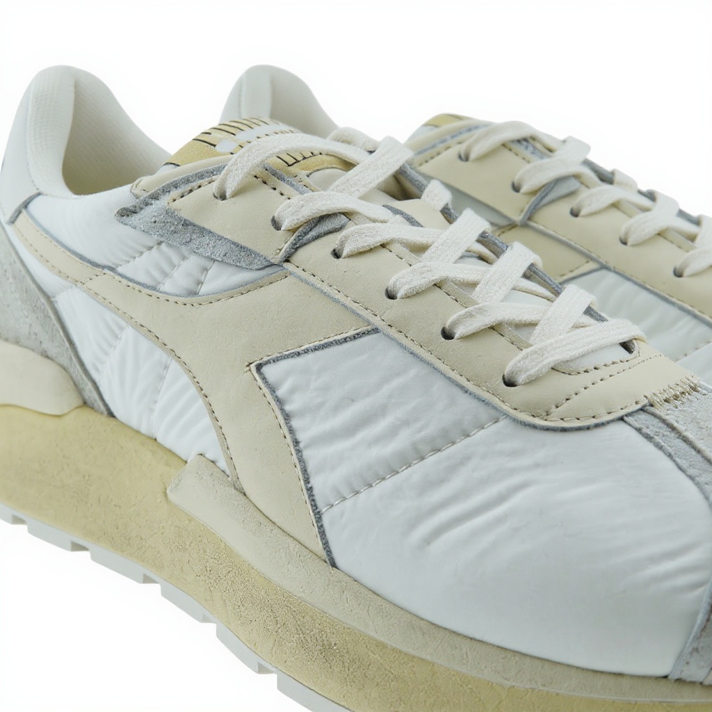 Primer plano de las deportivas DIADORA blancas, mostrando la textura de los materiales deportivo, tecno y piel, y detalles de la suela.