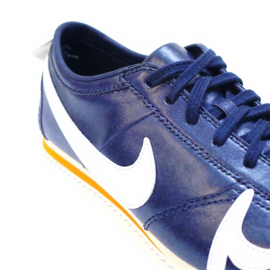 Primer plano detallado de una zapatilla deportiva NIKE azul, mostrando la textura de la suela BLOK, el material exterior de napa y las costuras.