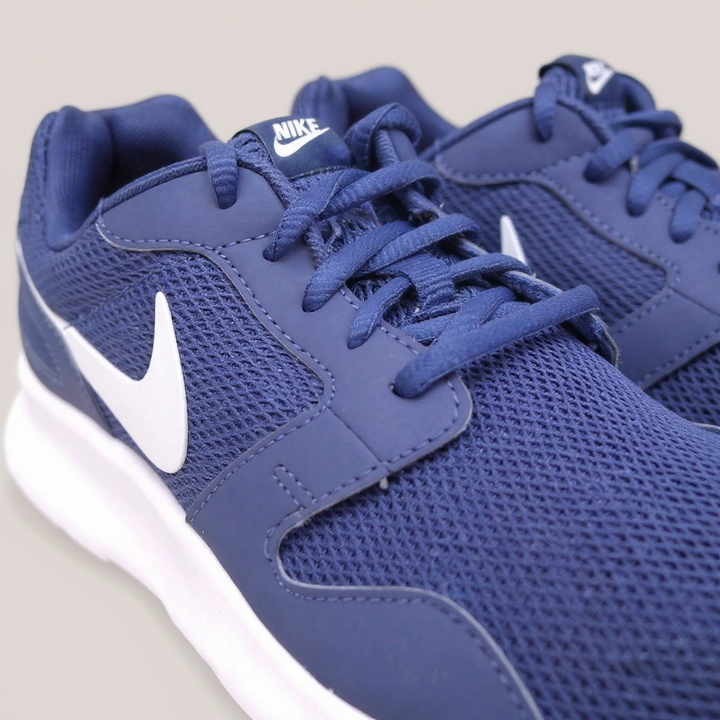 Detalle técnico de las zapatillas NIKE deportivas azules y blancas, mostrando la textura de la malla, la suela y los acabados.